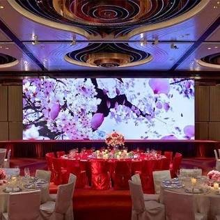 A large LED wall showing blossoms behind a banquet stage