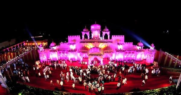 Aerial view of a palace-style wedding venue lit pink at night